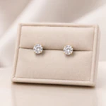 Puces d'oreilles brillantes à cristal rond transparent et monture dorée dans un écrin crème