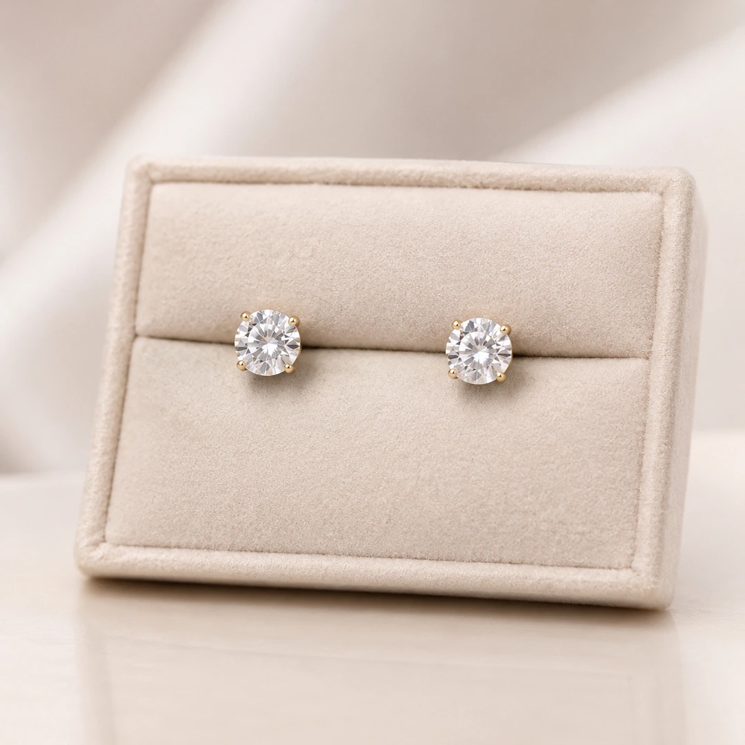 Puces d'oreilles brillantes à cristal rond transparent et monture dorée dans un écrin crème