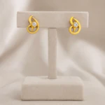 Puces d'oreilles arabesque dorées serties d'un cristal rond sur présentoir en T