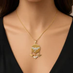 Collier médaillon rond doré orné d'une libellule en strass et de petits papillons, porté au cou