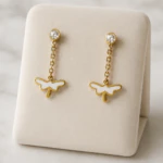Boucles d'oreilles pendantes dorées à puce cristal, chaînette et papillon blanc sur présentoir