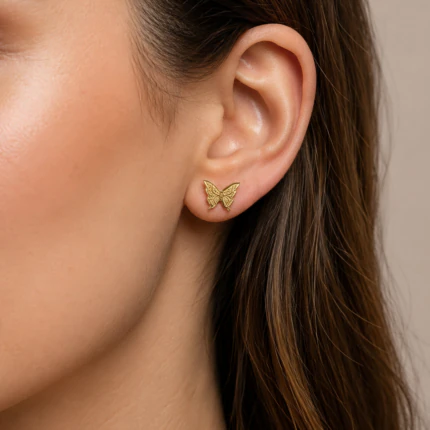 Puce d'oreille papillon dorée ajourée portée à l'oreille, vue rapprochée