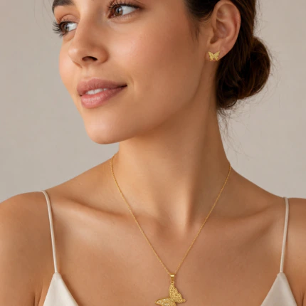 Parure dorée femme portée : collier papillon ajouré et puces d'oreilles papillon assorties
