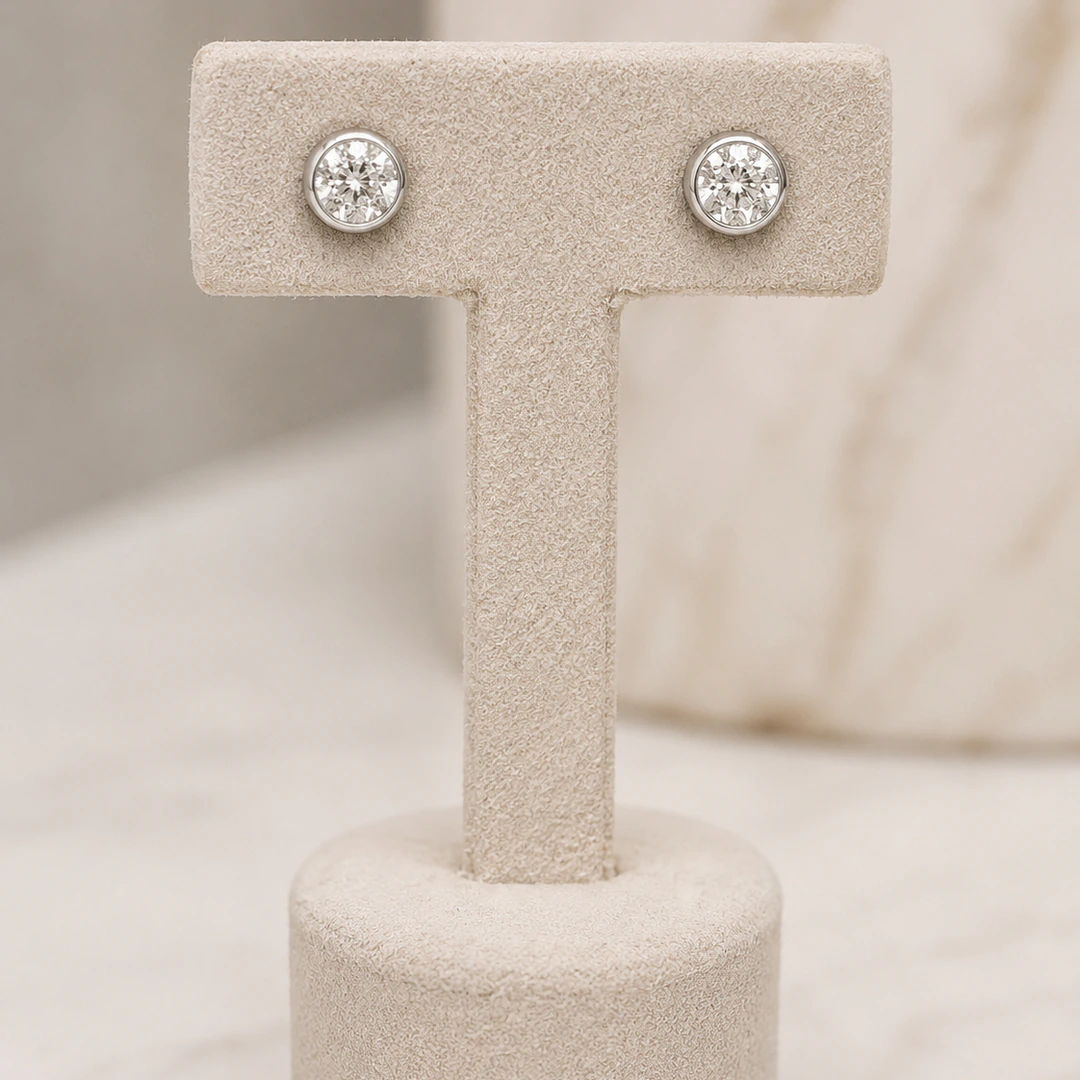 Puces d'oreilles rondes argentées pavées de strass sur présentoir en T beige