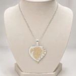 Pendentif cœur argenté à cœur intérieur doré texturé et bordure de strass sur buste
