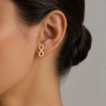 Boucle d'oreille motif infini dorée à strass portée à l'oreille, vue rapprochée