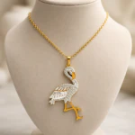Pendentif flamant serti de strass aux pattes dorées sur chaîne dorée, présenté sur buste