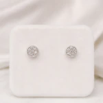 Puces d'oreilles rondes argentées pavées de strass transparents sur présentoir blanc