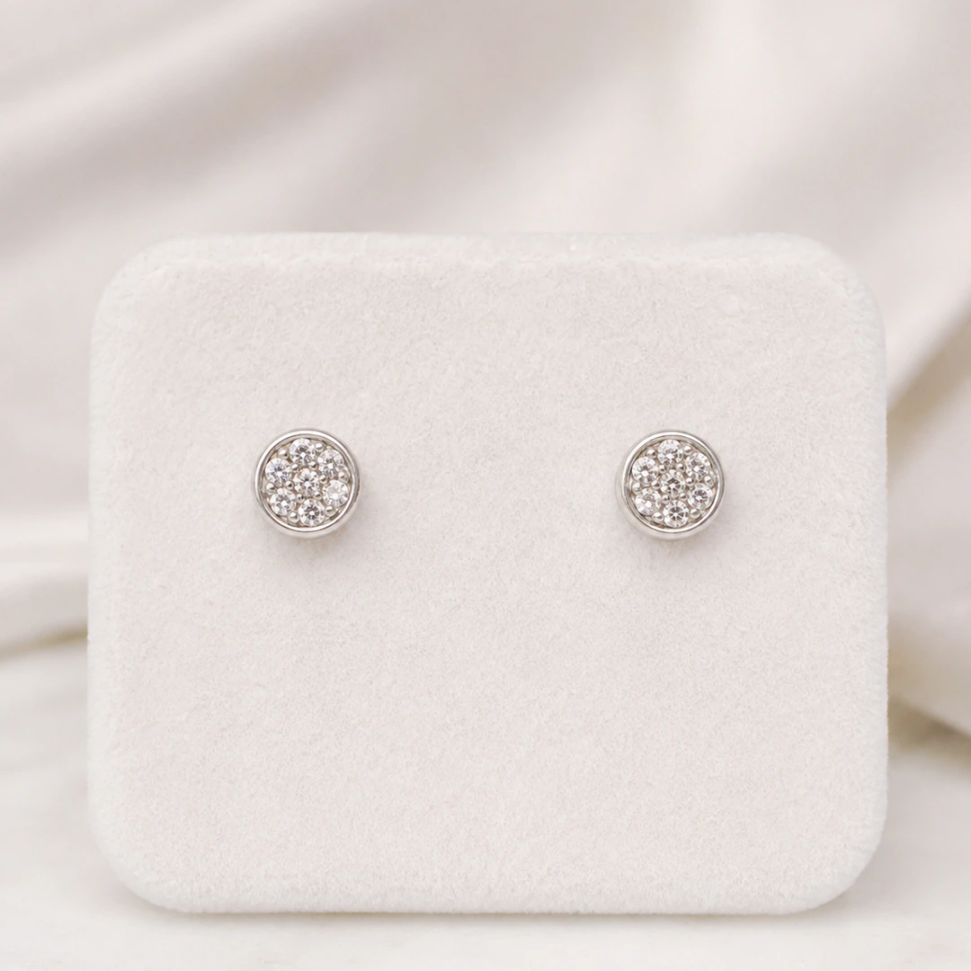 Puces d'oreilles rondes argentées pavées de strass transparents sur présentoir blanc