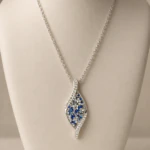 Pendentif argenté en forme de vague pavé de strass bleus et blancs sur buste beige