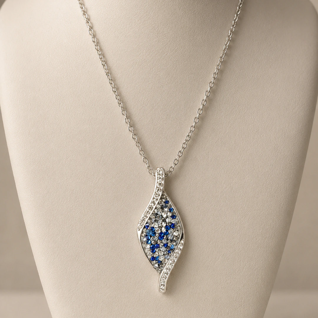 Pendentif argenté en forme de vague pavé de strass bleus et blancs sur buste beige