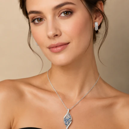 Parure argentée femme portée : collier pendentif allongé à strass bleus et créoles pavées de strass