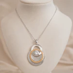 Pendentif argenté à disques superposés texturés, cercle de strass champagne et cristal sur buste