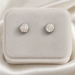 Puces d'oreilles rondes argentées à cristaux scintillants dans un écrin en velours gris