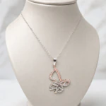 Pendentif papillon ajouré aux reflets argentés et rosés sur buste de présentation gris
