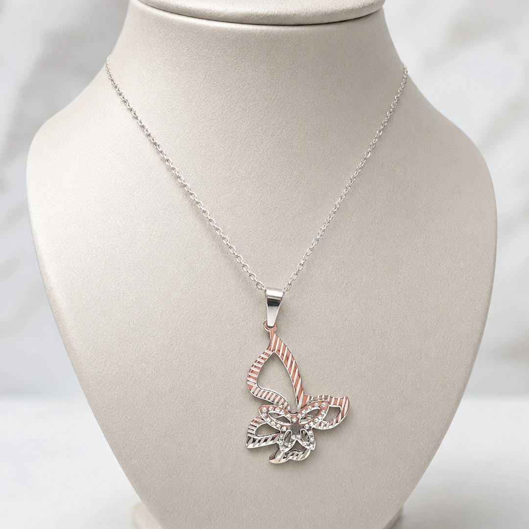 Pendentif papillon ajouré aux reflets argentés et rosés sur buste de présentation gris