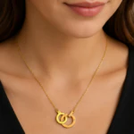 Collier doré à deux anneaux entrelacés sertis de petits strass porté au cou