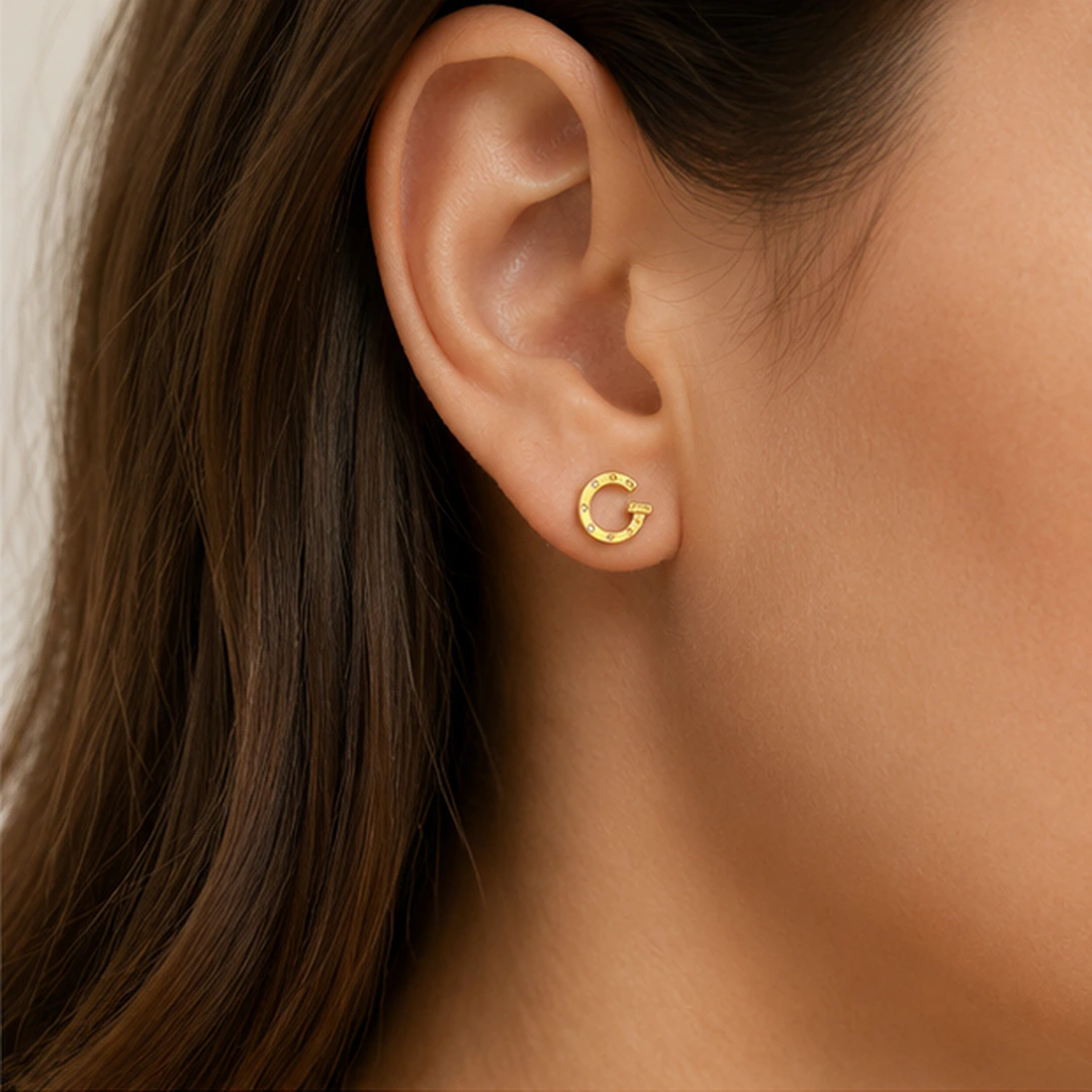 Boucle d'oreille ronde ouverte dorée à petits strass portée à l'oreille, vue de profil