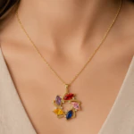Collier chaîne fine doré à pendentif rond de pierres navette multicolores porté au cou