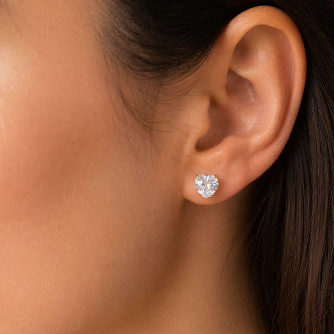 Puce d'oreille cœur en cristal transparent portée à l'oreille, vue rapprochée