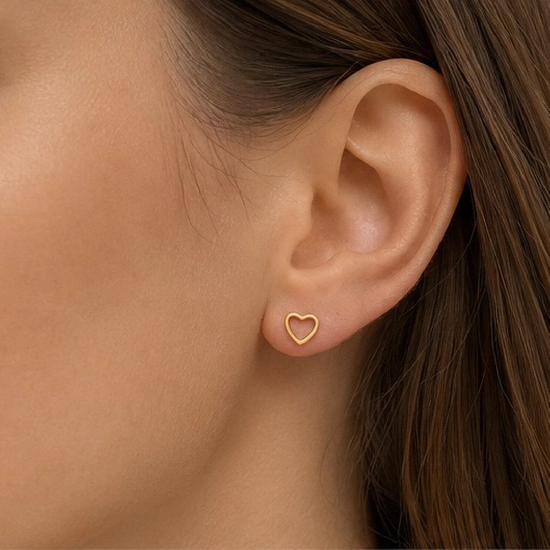 Puce d'oreille cœur ajouré dorée portée à l'oreille, vue rapprochée