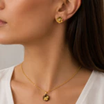 Parure dorée femme portée : collier pendentif fleur dorée et noire et puces d'oreilles fleur