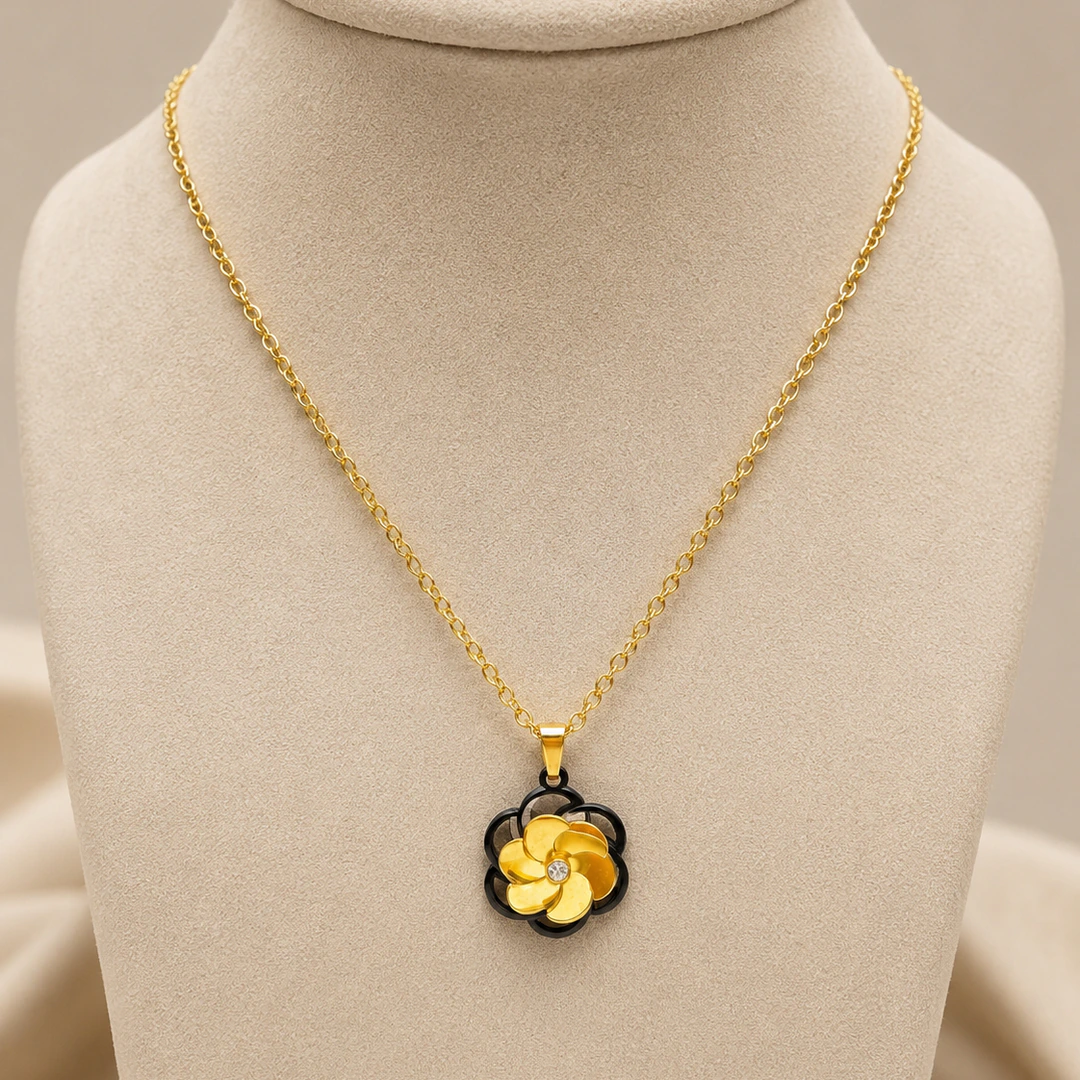 Pendentif fleur à pétales dorés sur contour noir et strass central, chaîne dorée sur buste