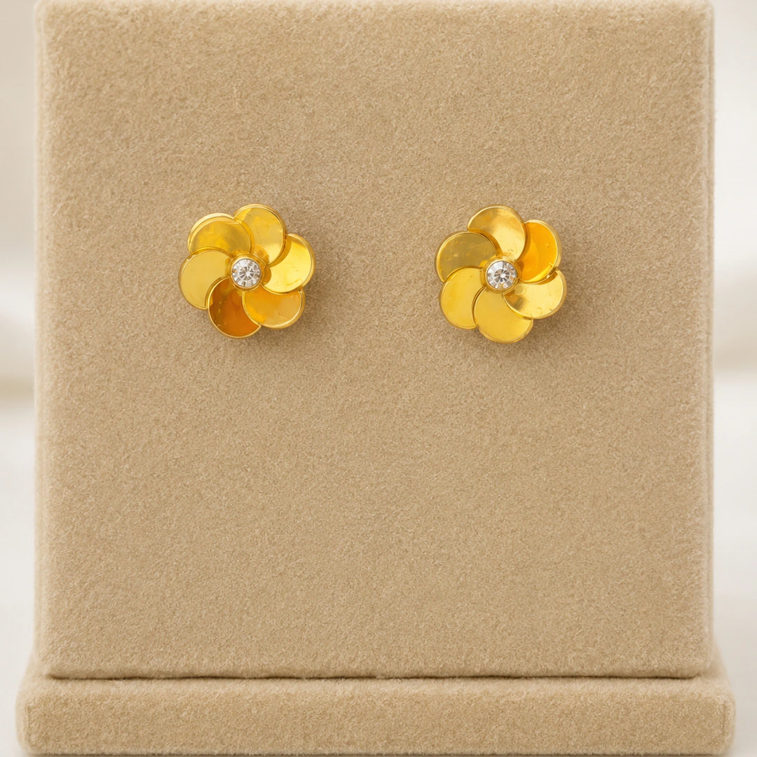 Puces d'oreilles fleur dorées à pétales superposés et strass central sur présentoir beige