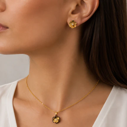 Parure dorée femme portée : collier pendentif fleur dorée et noire et puces d'oreilles fleur