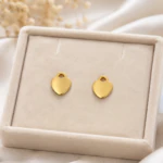 Puces d'oreilles cœur dorées polies dans un écrin en velours beige