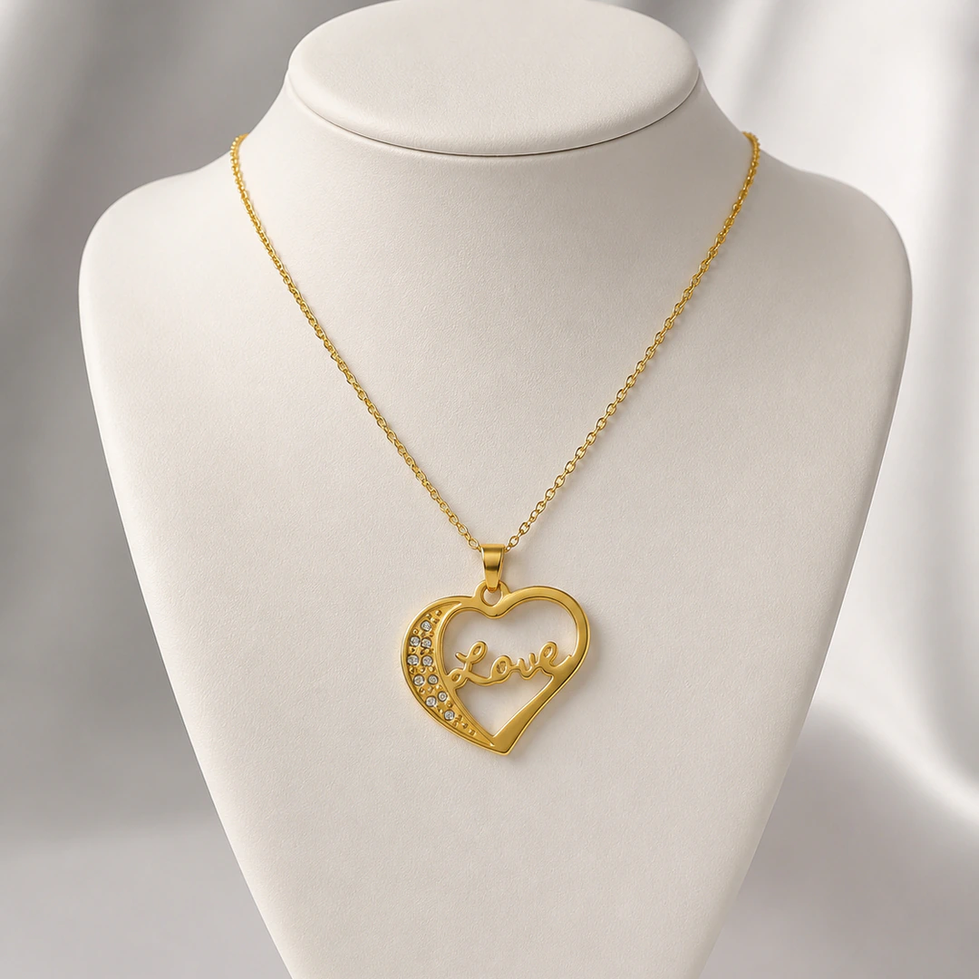 Pendentif cœur ajouré doré traversé du mot Love sur chaîne fine, présenté sur buste blanc
