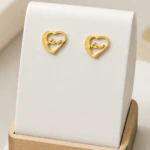 Boucles d'oreilles cœur ajouré dorées à inscription Love sur présentoir blanc