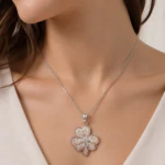 Collier chaîne argentée à pendentif trèfle travaillé en filigrane porté au cou