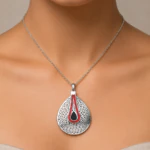 Collier argenté à grand pendentif goutte perforé orné d'une ligne de strass rouges porté au cou