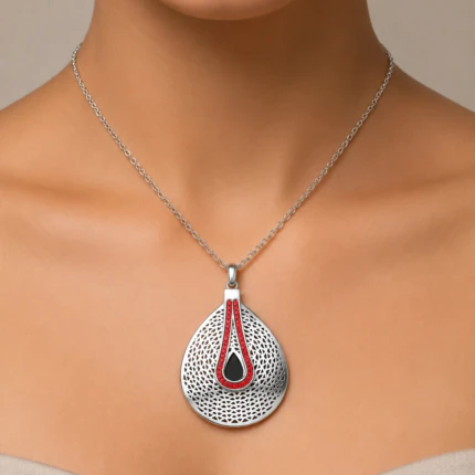 Collier argenté à grand pendentif goutte perforé orné d'une ligne de strass rouges porté au cou