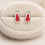 Boucles d'oreilles goutte argentées serties de strass rouges sur coussin en velours crème