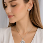 Parure argentée femme portée : collier médaillon rond floral ajouré et puces d'oreilles fleur