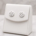 Boucles d'oreilles fleur ajourée argentées en forme de rose sur présentoir blanc