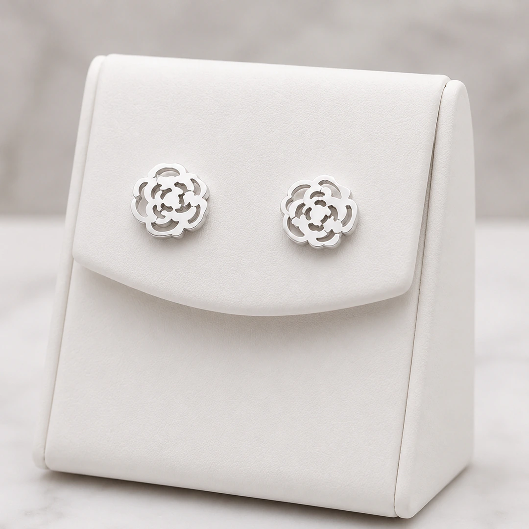 Boucles d'oreilles fleur ajourée argentées en forme de rose sur présentoir blanc