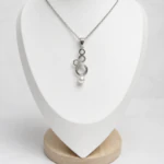 Pendentif argenté à anneaux superposés terminé par une perle blanche sur buste blanc