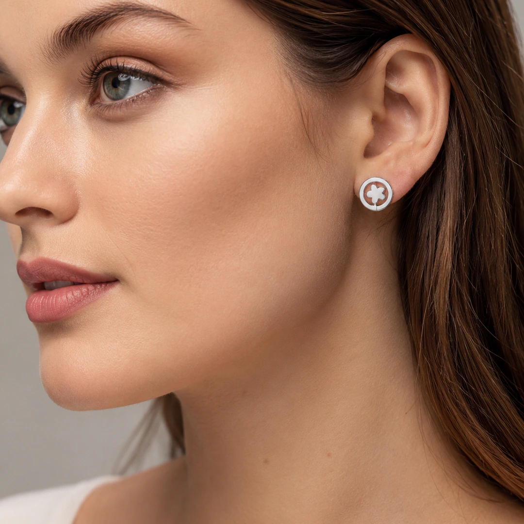Puce d'oreille ronde argentée à fleur blanche portée à l'oreille, vue de profil