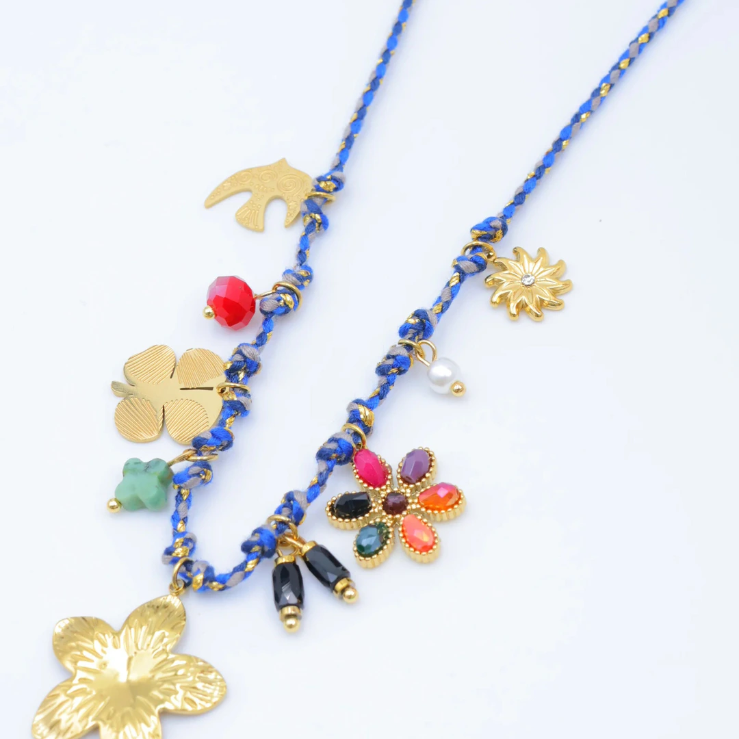 Collier cordon bleu à breloques fleurs dorées, trèfle, oiseau, perle blanche et pierres colorées sur fond blanc