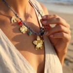 Collier bohème femme à cordon bleu tressé et breloques dorées et colorées, porté au cou à la plage