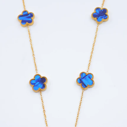 Gros plan sur les trèfles bleu irisé au contour doré perlé et la chaîne fine du collier