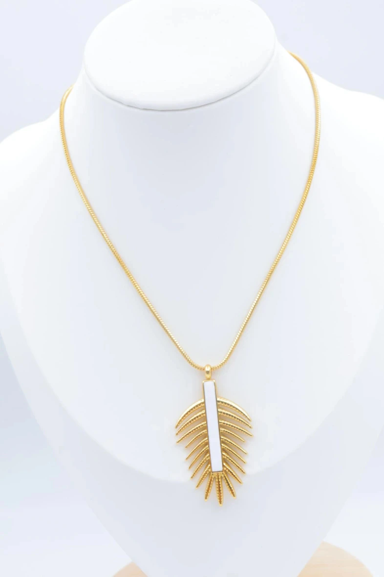 Collier pendentif feuille dorée à barrette blanche verticale sur un buste de présentation blanc