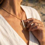 Collier doré femme à pendentif feuille et détail blanc