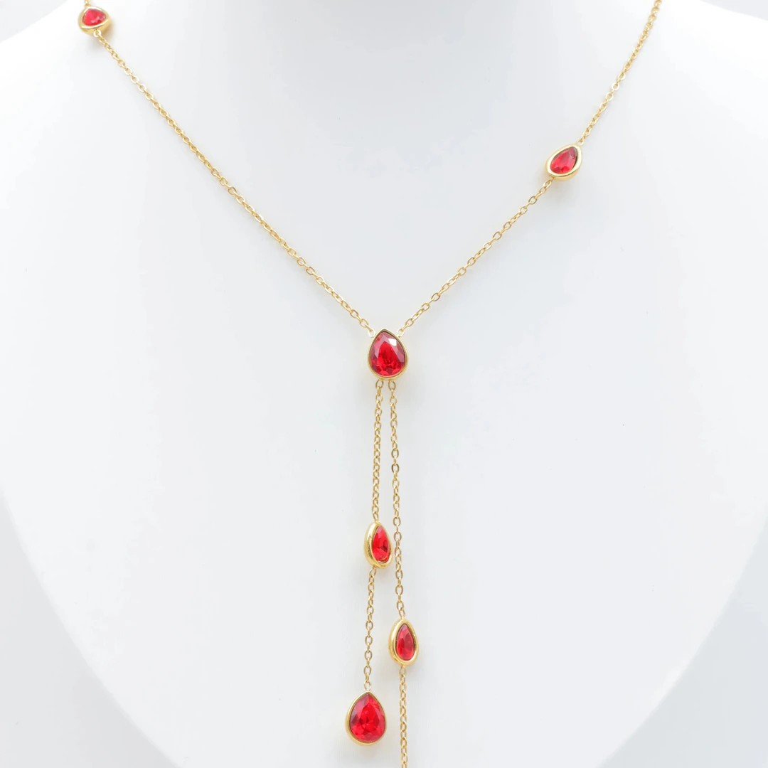 Collier chaîne fine dorée à pierres rouges en forme de goutte et double chute centrale sur buste blanc
