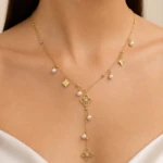Collier doré femme en Y à petits trèfles et perles blanches pendantes, porté au cou