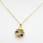 Gros plan du pendentif fleur aux pétales facettés rose, vert, bleu et jaune sur chaîne fine dorée