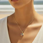 Collier doré femme à pendentif fleur multicolore en pierres facettées, porté au cou en bord de mer